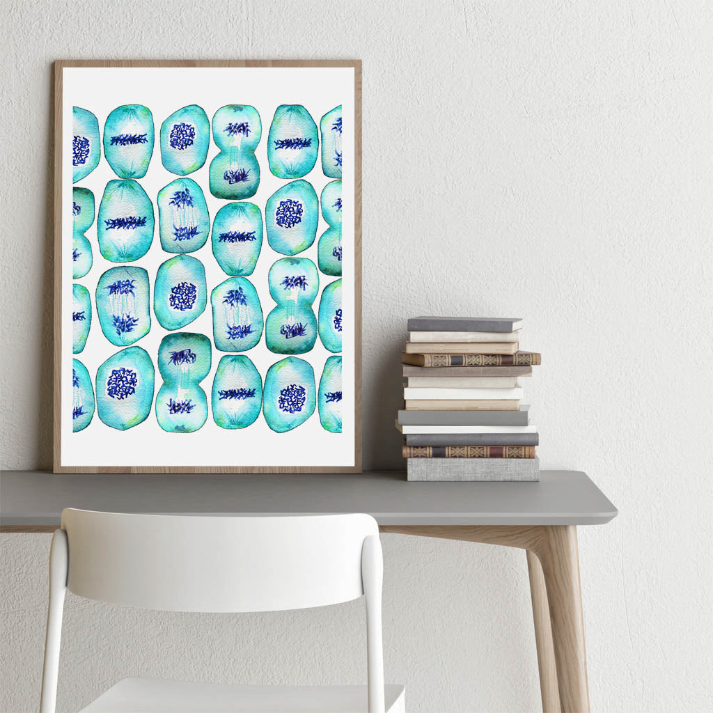 Mitosis art print in wooden frame on desk.